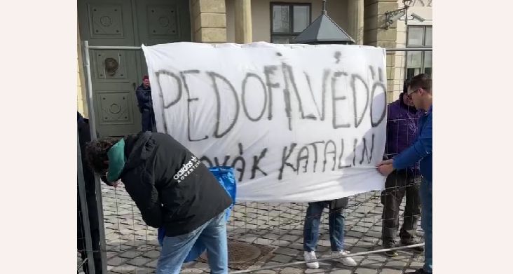 „Pedofilvédő Novák Katalin” – olvasható a Sándor-palota előtti molinón